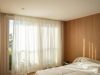 A bright bedroom with sheer curtains and sunlight.