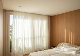 A bright bedroom with sheer curtains and sunlight.