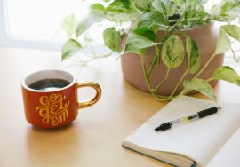 black retractable pen on opened book beside red and white go get'em-printed coffee cup