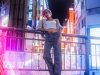 Woman poses in a neon-lit city at night.