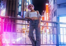 Woman poses in a neon-lit city at night.