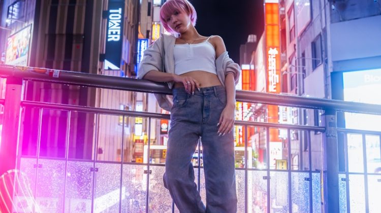 Woman poses in a neon-lit city at night.