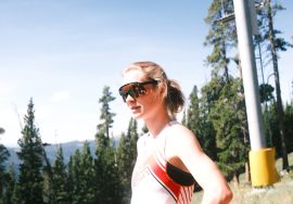 Woman pauses near a ski lift on a sunny day.