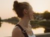 Woman smiles, enjoying the sunset by the river.