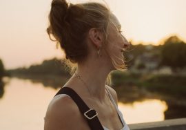 Woman smiles, enjoying the sunset by the river.