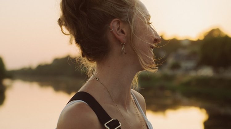 Woman smiles, enjoying the sunset by the river.