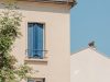 A building's corner with blue shutters and chimney.