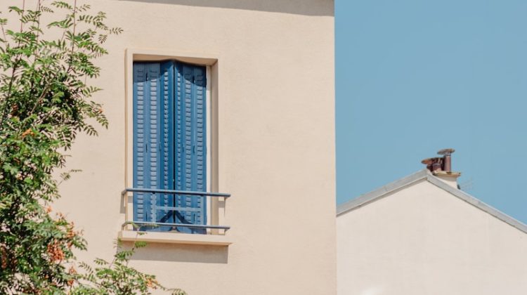 A building's corner with blue shutters and chimney.