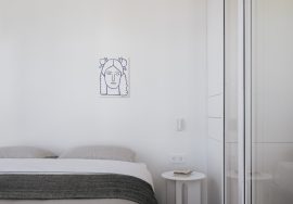 Minimalist bedroom features a bed, art, and a small table.