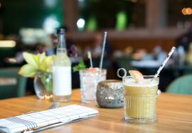 filled liquid in glass beside fork and table knife near bottle on table