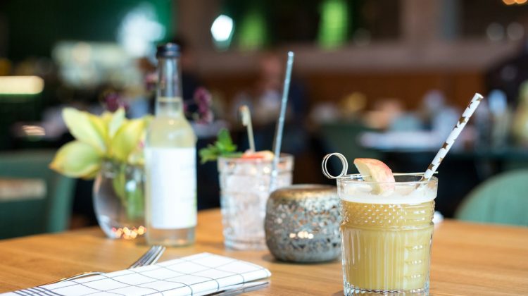 filled liquid in glass beside fork and table knife near bottle on table