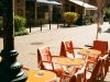 Outdoor cafe tables and chairs line a sunny street.