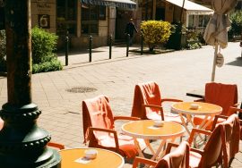 Outdoor cafe tables and chairs line a sunny street.
