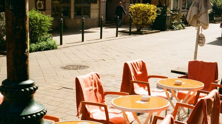 Outdoor cafe tables and chairs line a sunny street.