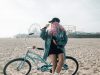 Woman with pink hair posing near a bicycle on the beach.