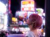 Woman gazes at bright neon signs in the city.