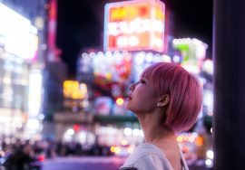 Woman gazes at bright neon signs in the city.