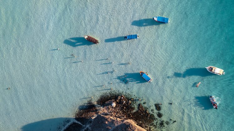 Boats float in beautiful, clear blue water.