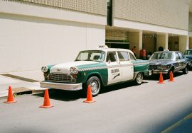 A vintage taxi parked near some traffic cones.