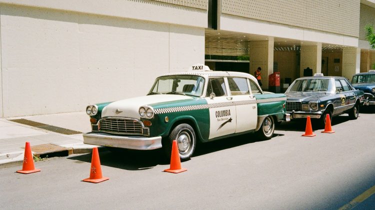 A vintage taxi parked near some traffic cones.